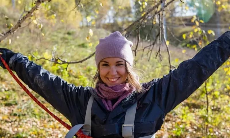 Улыбающаяся участница в страховочной системе после прохождения маршрута