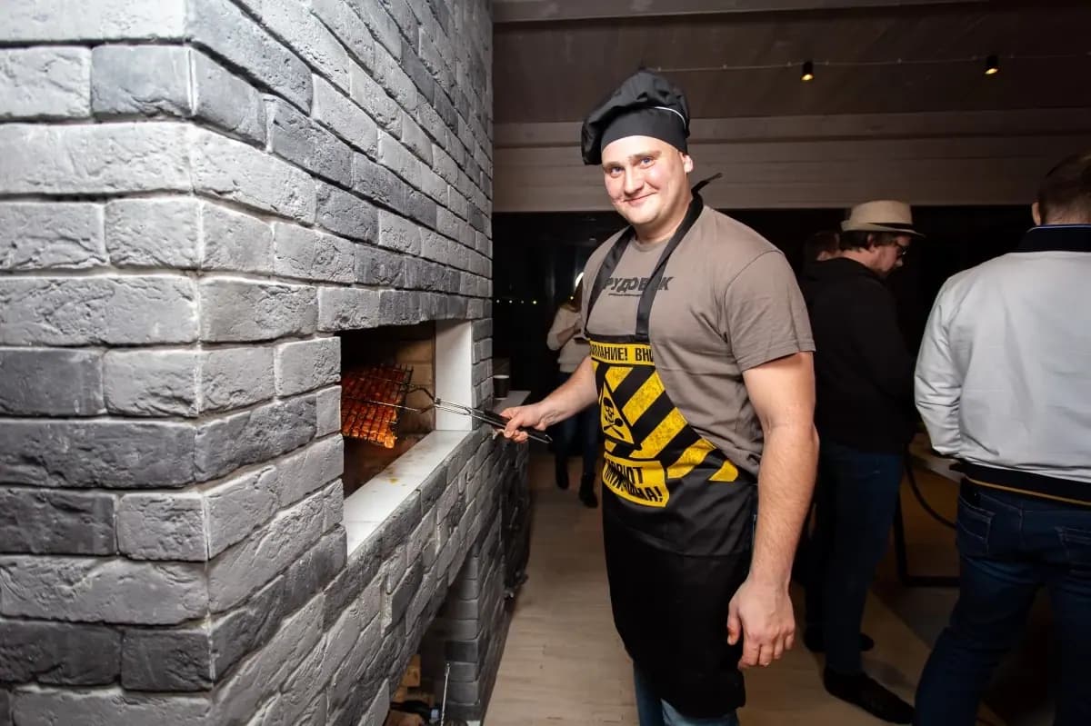 Гость готовит мясо на встроенном мангале гриль-домика