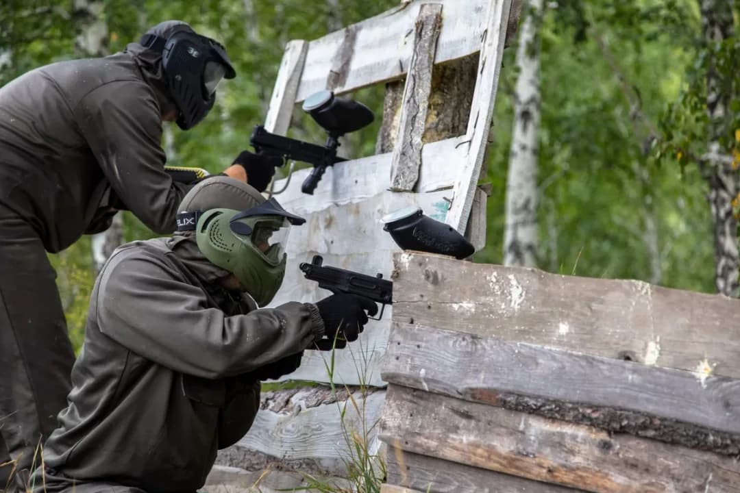 Игроки на пейнтбольном полигоне с деревянными укрытиями